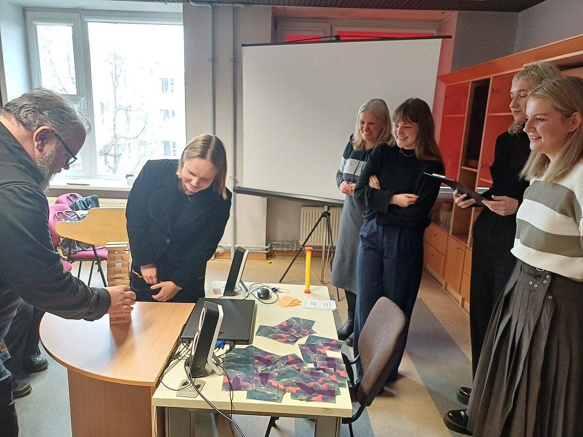 Studentes Laura Anna Badūne, Sofija Keiča un Katrīna Liepiņa kopā ar programmas direktori doc. Intu Urbanoviču prezentē “Latvistikas” studentu veidotu spēli